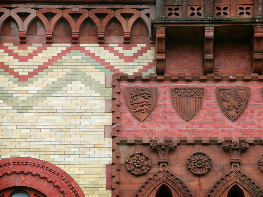 A building made up of pink, red and cream coloured bricks laid in amazing patterns including zig zags