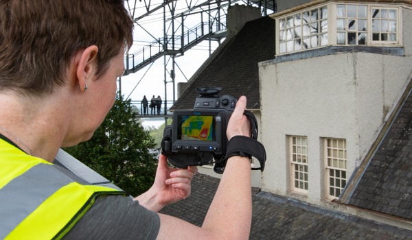 A heritage scientist pointing an infrared camera at the Hill House